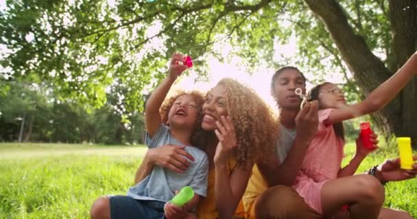 Familj limning och blåser bubblor i park — Stockvideo