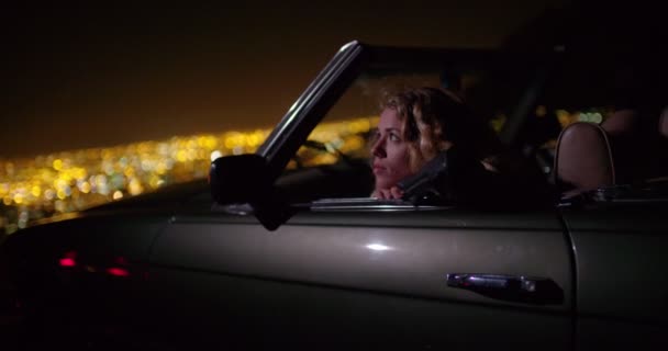 Mujer buscando luces nocturnas de la ciudad desde el coche — Vídeos de Stock