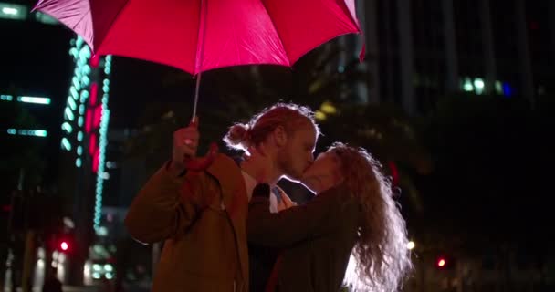 Пара поцелуев под зонтиком в городе — стоковое видео