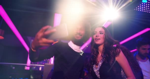 Pareja alegre en fiesta de discoteca tomando selfies en la pista de baile — Vídeo de stock