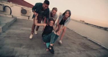 Bir kaykay üzerinde kız arkadaşlarıyla çatı üzerinde