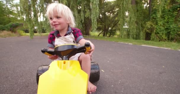 Niño jugando con su coche de juguete en la carretera — Vídeo de stock