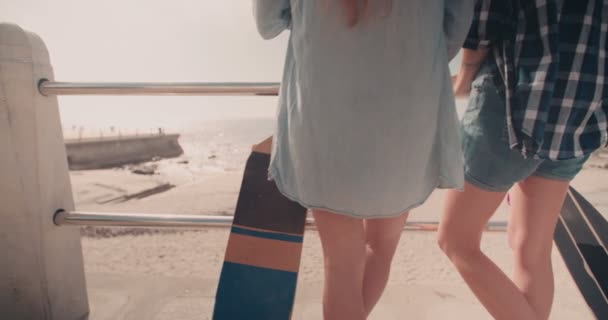 Chicas en pantalones cortos de pie en la playa con monopatines — Vídeos de Stock