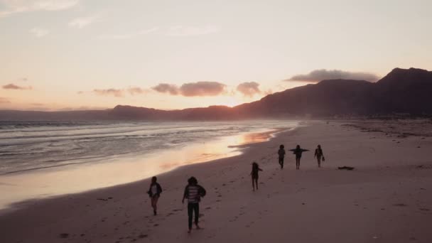 Друзья, наслаждающиеся прогулкой на пляже на закате — стоковое видео