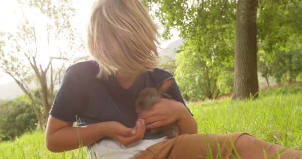 Niño cuidando de un conejito fuera — Vídeos de Stock