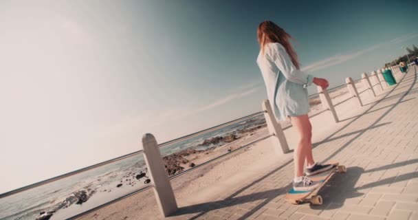 Bruslař dívka na koni svého skateboardu podél pláže — Stock video