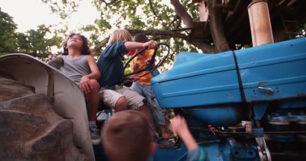 Дети играют на тракторе в летний день — стоковое видео