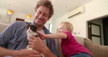 Kedi evlat için evde beslenen hayvan kanepede tutan baba