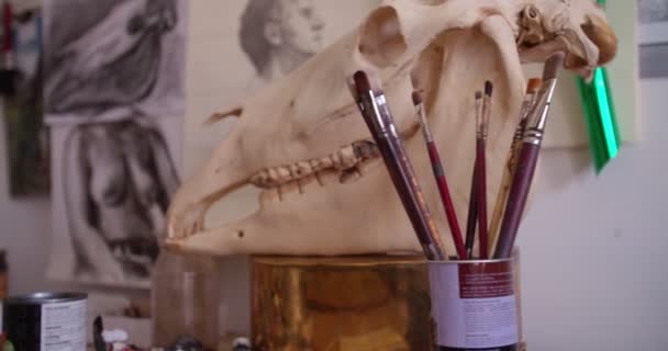 Художник рисует кисти в кружке на столе в художественной студии — стоковое видео