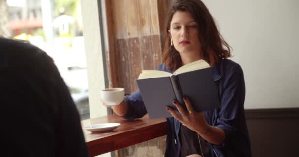 Meisje drinken koffie en lezen boek in Cafe — Stockvideo