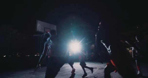 Jugadores de baloncesto jugando en la cancha durante la noche — Vídeos de Stock