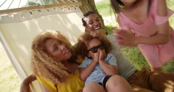 Багатоетнічна сім'я розслабляється разом на гамаку — стокове відео