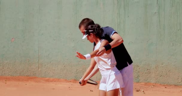 Entrenador de tenis enseñando tenis joven en pista de arcilla — Vídeos de Stock