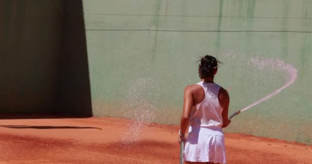 Jugadora de tenis limpiando cancha de arcilla con manguera — Vídeos de Stock