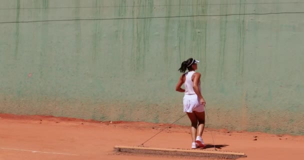 Jugadora de tenis limpiando pista de arcilla antes de practicar tenis — Vídeos de Stock