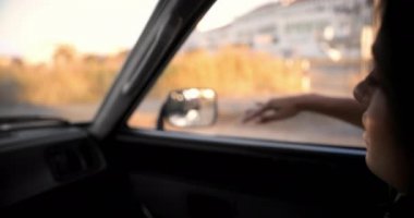 Gün batımında kolu arabada olmayan bir kadın.