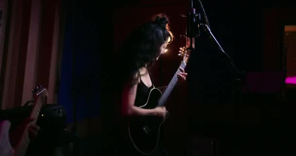 Cantante femenina tocando la guitarra con guitarrista masculino en estudio de música — Vídeo de stock