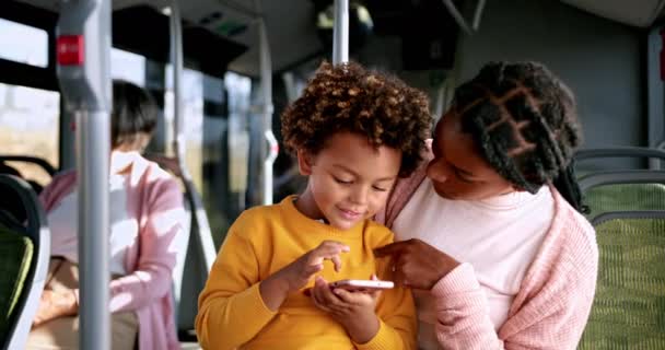 Afro-Amerikaanse jongen spelen met telefoon op moeder schoot in de bus — Stockvideo