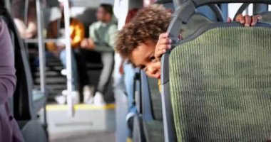 Afro-Amerikalı küçük çocuk halk otobüsünde dikiz oyunu oynuyor.