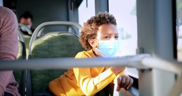 Афро-американец в маске ковида, выглядывающий в окно автобуса — стоковое видео