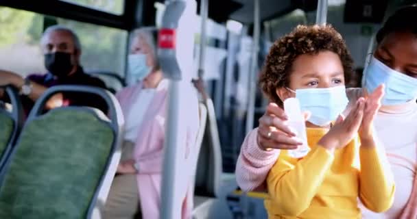 Afro-americano madre con covid maschera disinfezione figlio mani dentro autobus — Video Stock