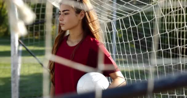 Jugadora de fútbol femenina confiada sosteniendo la pelota en el campo de fútbol — Vídeos de Stock