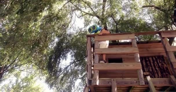 Ragazzino che gioca con il binocolo su una casa sull'albero — Video Stock