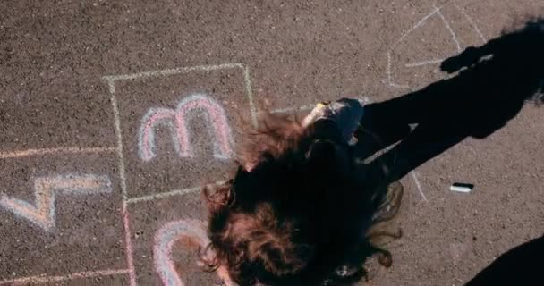 Nettes kleines Mädchen springt und spielt Hopscotch auf Asphaltstraße — Stockvideo