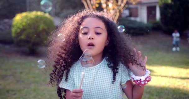 Kleines Mädchen pustet Blasen mit selbstgebasteltem Zauberstab im Garten — Stockvideo