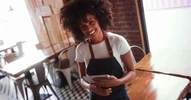 Σερβιτόρα κρατώντας ψηφιακό δισκίο χαμογελώντας κοιτάζοντας κάμερα στο εστιατόριο — Αρχείο Βίντεο