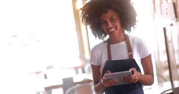 Tarjoilija työskentelee digitaalisen tabletin kanssa hymyillen ravintolassa — kuvapankkivideo