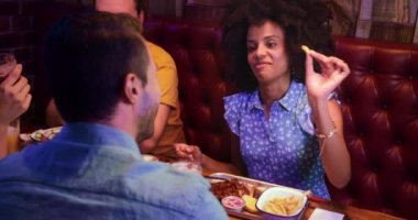Afro-Amerikalı bir kadın retro restoranda arkadaşına patates kızartması yediriyor.