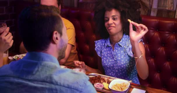 Afro-americana mujer alimentación papas fritas a amigo en retro restaurante — Vídeos de Stock