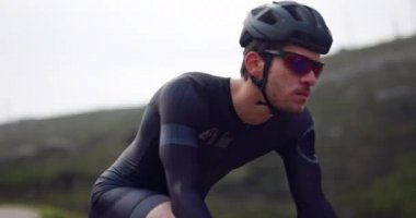 Dağda siyah bisiklet süren profesyonel bir bisikletçi.