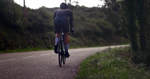 Male cyclist riding sports bike uphill on a forest road — Stock Video