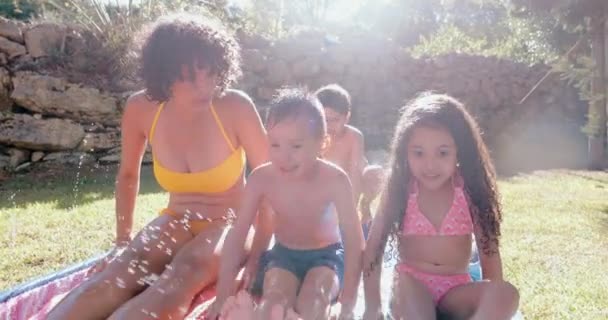 Madre e hijos deslizándose en el tobogán de agua en el jardín — Vídeos de Stock
