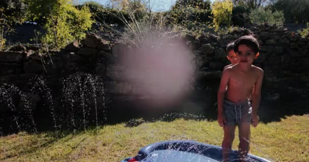 Niño pequeño deslizándose y rodando en el tobogán de agua del jardín — Vídeo de stock