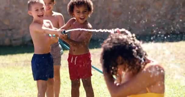 Група дітей розбризкує воду шлангом на мамі — стокове відео