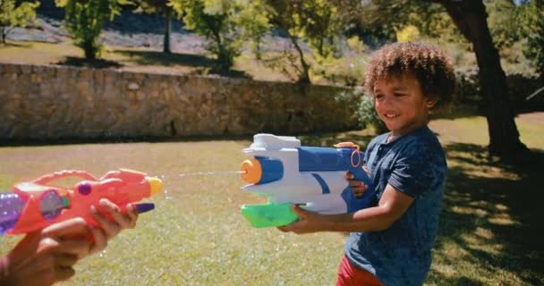 Mutter spielt mit Wasserpistolen im Garten mit kleinem Jungen — Stockvideo