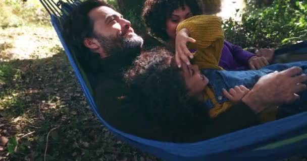 Familie som ligger og leker i en hengekøye i skogen – stockvideo