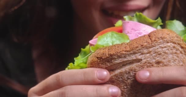 Mujer joven sosteniendo y comiendo sándwich — Vídeo de stock