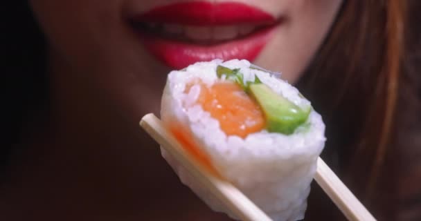 Young woman mouth eating sushi piece on chopsticks — Stock Video