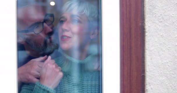 Idősebb pár néz együtt kívülről az ablakból. — Stock videók
