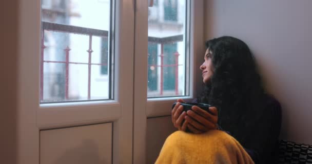 Latina mulher sentada olhando pela janela bebendo café — Vídeo de Stock