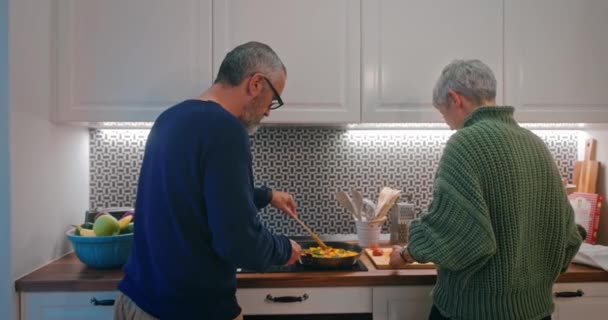 Starsza para przygotowuje wspólną kolację w kuchni — Wideo stockowe