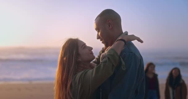 Multi-racial jovem casal abraçando na praia durante o pôr do sol — Vídeo de Stock
