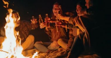 Bir grup arkadaş gece sahilde şenlik ateşinde içki içiyorlar.