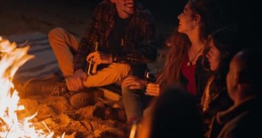 Gece arkadaşlarıyla şenlik ateşinde şarap içen kız.