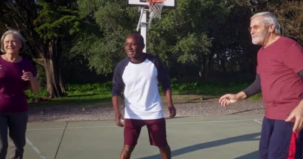 Старшая группа друзей, играющих в баскетбол на открытом воздухе — стоковое видео