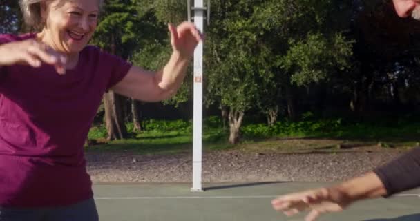 Senior vrouw en man basketbal spelen op de buitenplaats — Stockvideo